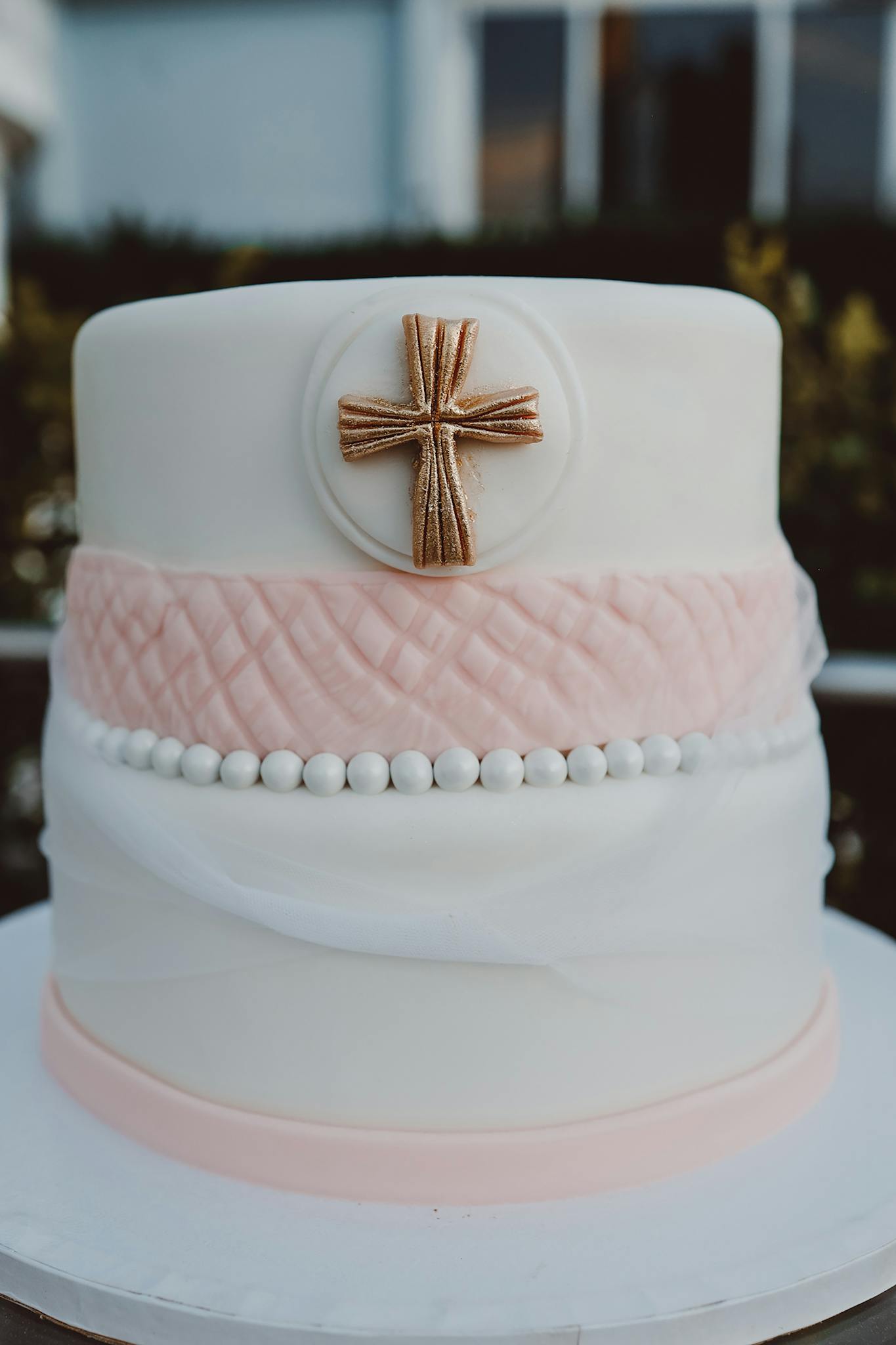 Beautiful pink and white cake decorated with a cross for a religious celebration.