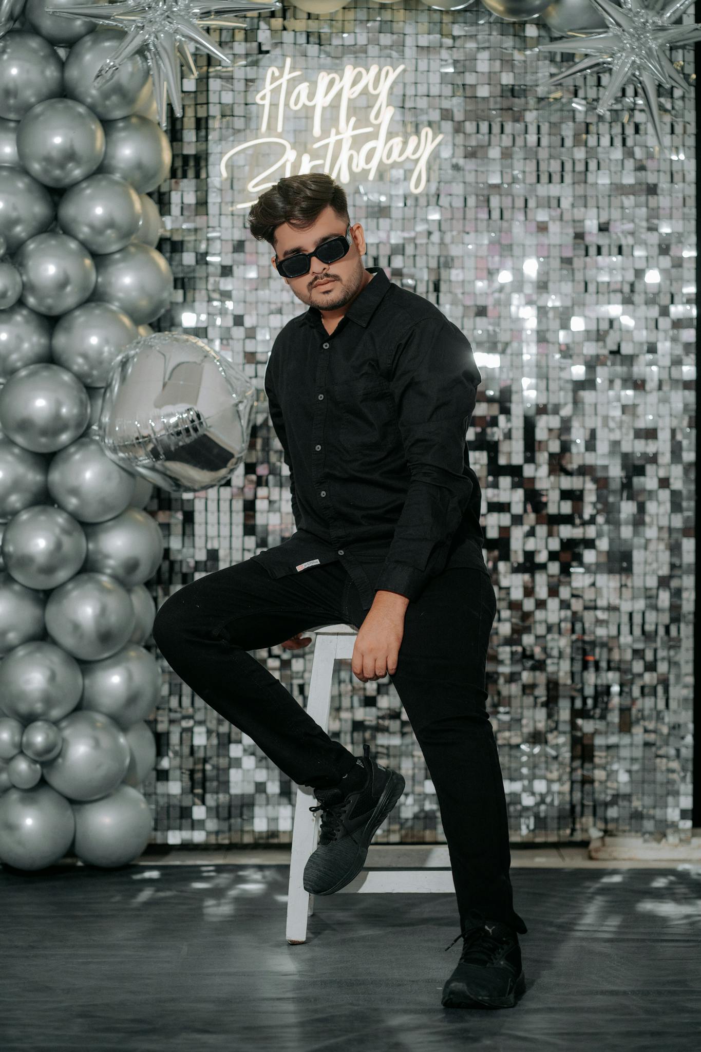 Young man in sunglasses at a chic birthday party with silver decor in Mumbai.